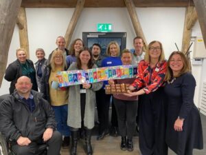 Image shows a group of training session attendees with two of those present holding a banner across the front of the group that reads Happy Birthday