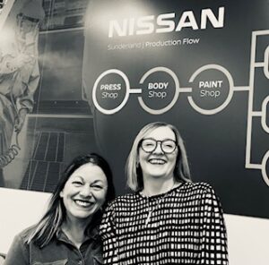 Lucy and Karen at Nissan, photographed under the Nissan logo