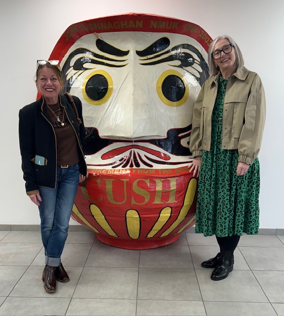 Lucy and Karen are standing proudly to either size of a giant, Japanese papier-mâché Hariko head.